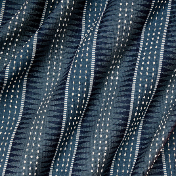 Close-up view of a fabric with a geometric pattern featuring stripes and dots in blue and white colors.