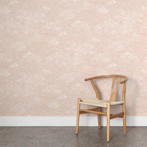 Wooden chair with beige cushion against decorative wallpaper.
