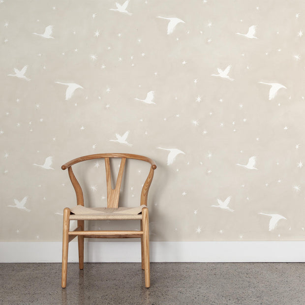 Wooden chair against a wall with subtle bird pattern wallpaper.