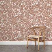 Wooden chair with beige cushion against a patterned wall.