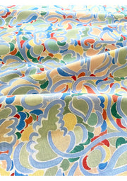 A fabric with a multicolored abstract pattern featuring various geometric and floral designs in beige, blue, green, red, and yellow.