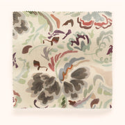 A fabric sample with a floral pattern in beige, blush, green, multi, pink, and purple colors on a verdigris metallic surface.