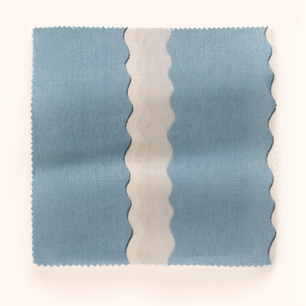 A piece of fabric with a double scroll stripe pattern, primarily in beige and blue colors.