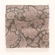 A piece of folk floral patterned fabric in brown, green, and purple colors.