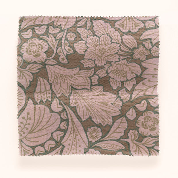 A piece of folk floral patterned fabric in brown, green, and purple colors.