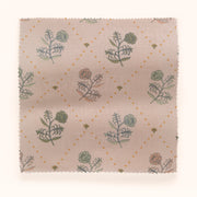 A swatch of floral patterned fabric in various colors including green, pink, and yellow on a beige background.