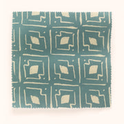 A yard of fabric with a geometric pattern featuring beige and white colors on a blue background.