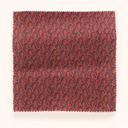 A yard of fabric with a red and pink microprint design featuring tree patterns.