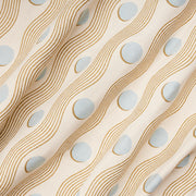 Close-up view of a fabric featuring a geometric pattern with cream-colored background, light blue circles, and mustard yellow lines.