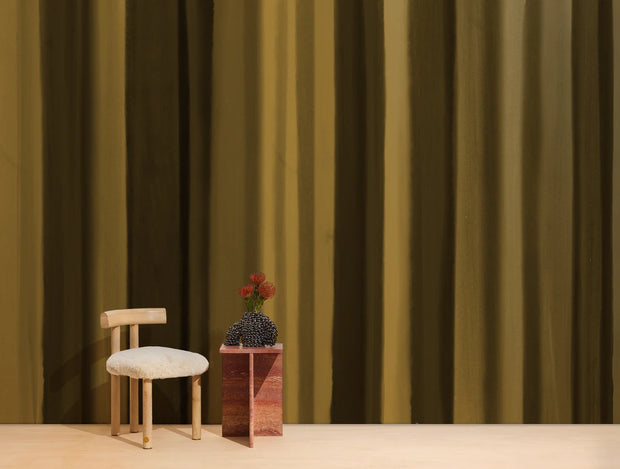 Small wooden chair with a white cushion and a small table with a vase against a striped curtain background