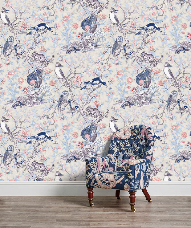A wall adorned with a floral and animal patterned wallpaper, featuring birds and flowers in a colorful design, with a chair in front of it. Tree of Life Wallpaper – Ivory | Elegant Botanical Wall Covering by Yard