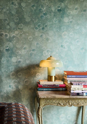 Decorative table with books and a lamp against a bubble-patterned wall.