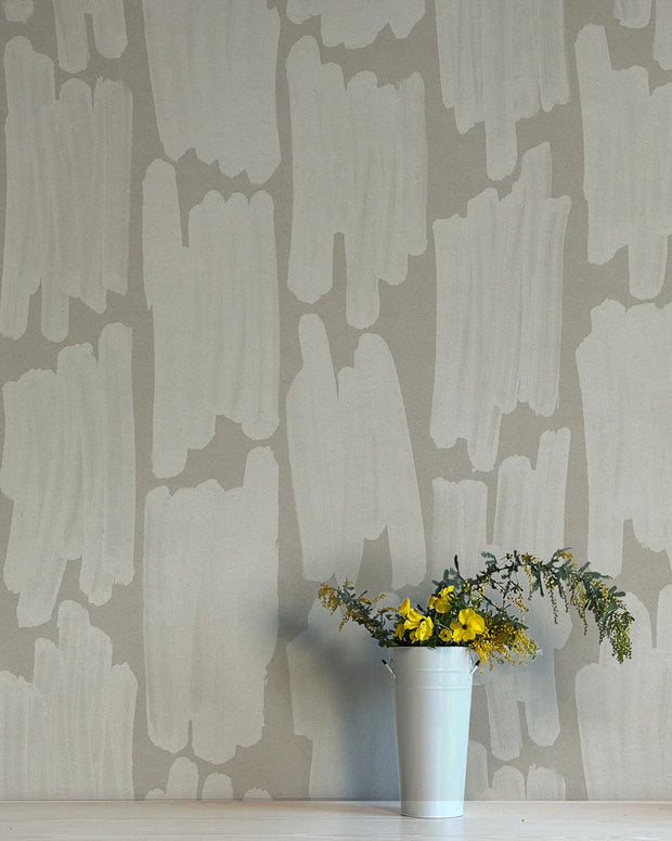 A section of wallpaper with an abstract geometric pattern in beige and white colors, with a vase of flowers in the foreground.