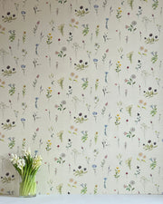A wallpaper with a floral pattern featuring various flowers in different shades of beige, blue, green, pink, and purple, displayed on a wall.