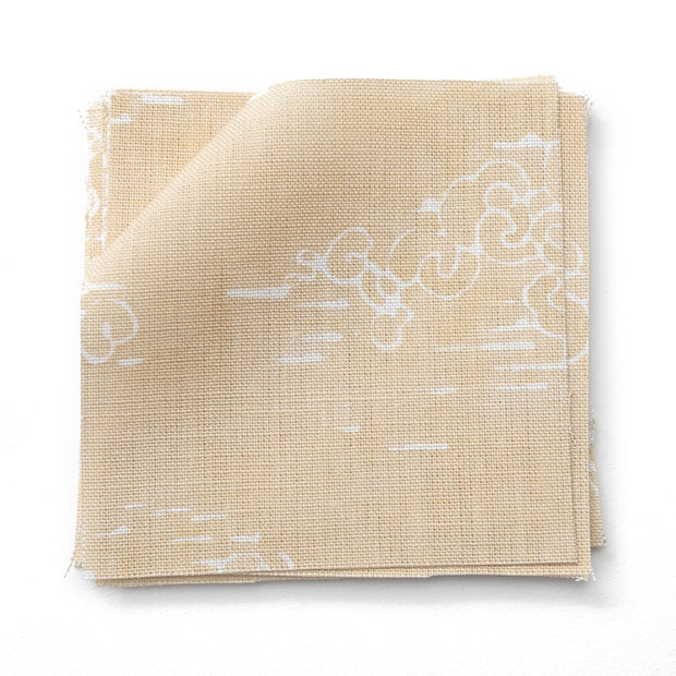 A folded piece of linen fabric with a white floral pattern on a beige background.