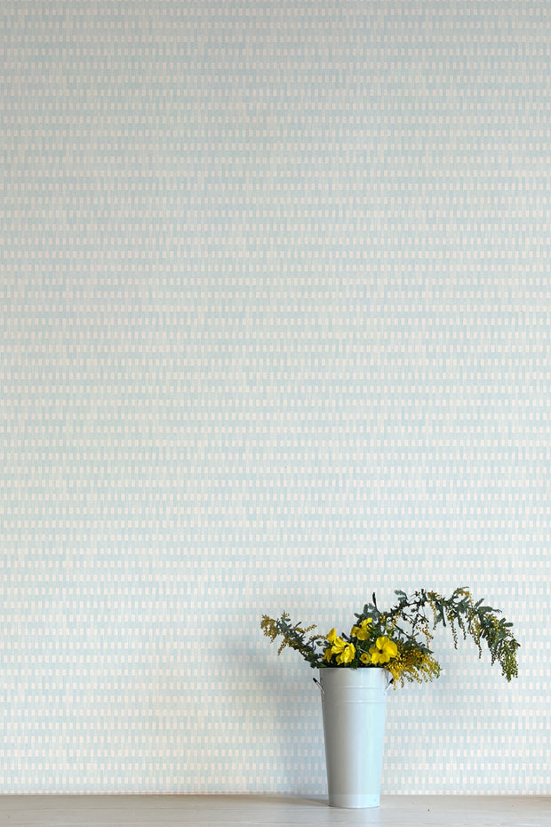 A section of light blue wallpaper with a geometric pattern of stripes, flanked by a white wall on one side and a vase with yellow flowers on the other - Patio Light Blue Wallpaper – Fresh Non-Woven Pattern Design