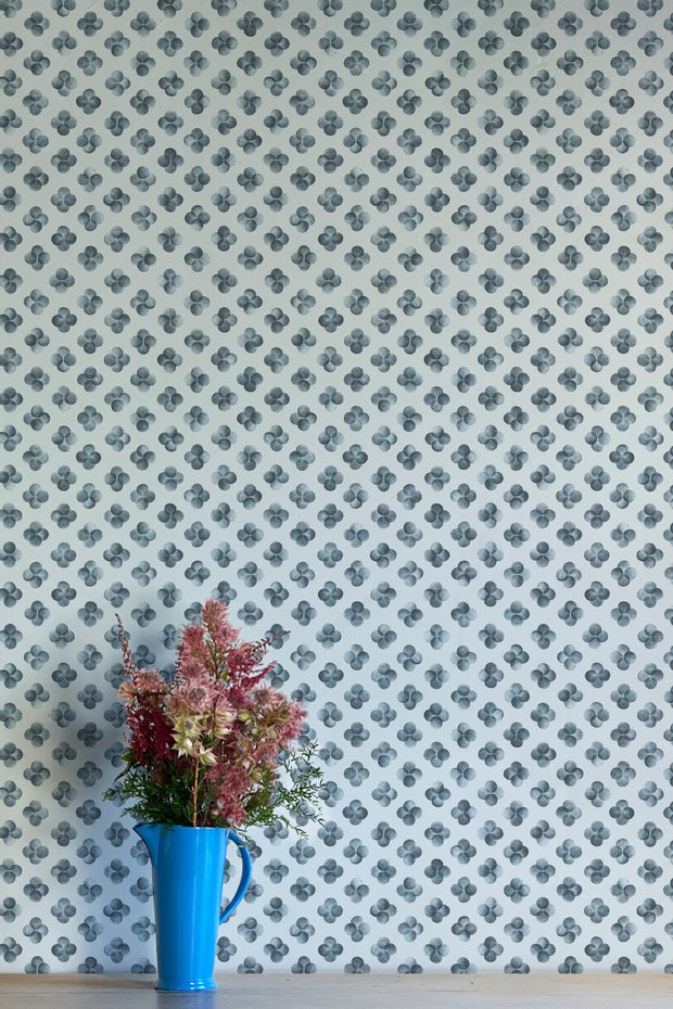 A wall adorned with blue wallpaper featuring a geometric pattern, in a room with a blue vase containing red flowers - Quattro Point Blue Wallpaper – Modern Non-Woven Double Roll