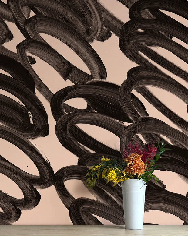A wall adorned with black and beige abstract wallpaper, featuring a vase with flowers in front.