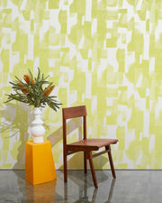 Wooden chair and yellow vase with greenery against a patterned yellow and white wall. Electric Sunshine on White Wallpaper – Agolise | Half-Drop 10 Yard Roll