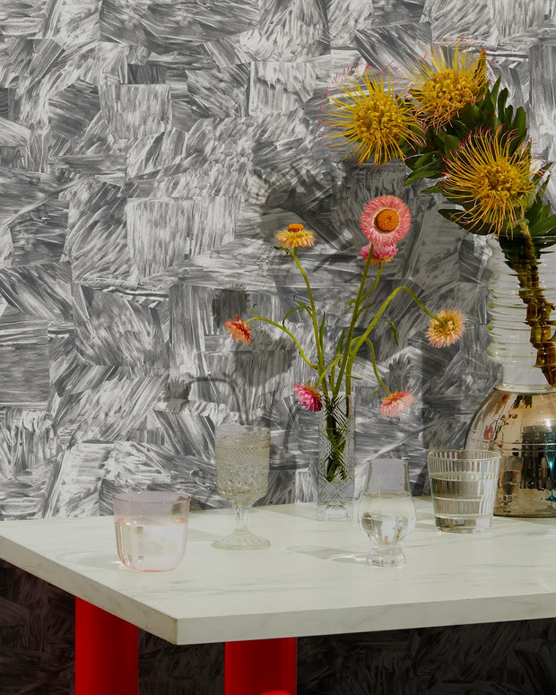 Table with flowers and glasses against a textured wall.