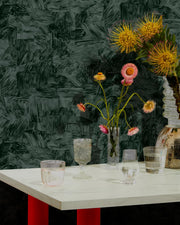 Table with flowers and glasses against a dark textured wall