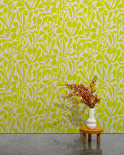 Green and white abstract patterned wallpaper with a small table and vase in the foreground.