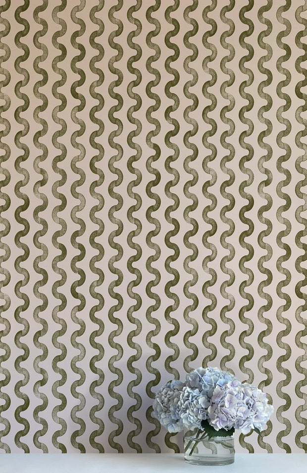 A wall adorned with green and white striped wallpaper, flanked by a vase with flowers in the foreground.