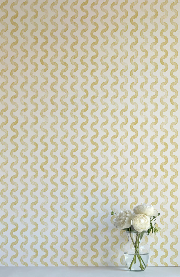 A wall adorned with a yellow and white geometric patterned wallpaper, featuring a vase with flowers in the foreground.