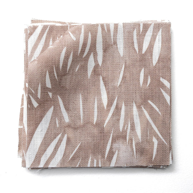 A yard of Windswept fabric in a dusty rose color with white abstract leaves pattern.