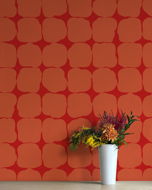 A wall adorned with orange geometric patterned wallpaper, featuring a white vase with flowers in front. Copia - WP Wallpaper by Blot | Non Woven Double Roll, 27” Trimmed